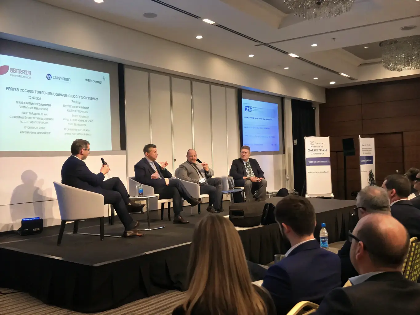 A dynamic image of a conference in Manchester, showcasing a panel discussion with industry experts and engaged audience members.